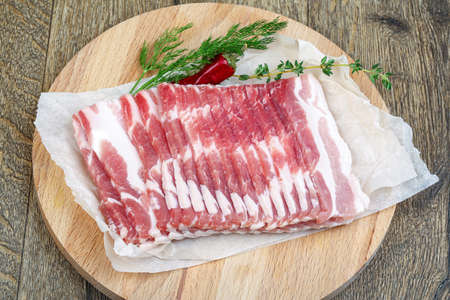 Raw sliced bacon ready for cooking on wood backgroundの写真素材