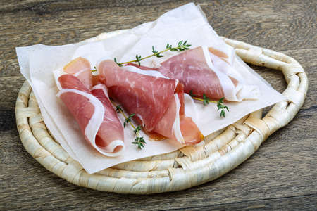 Italian Prosciutto meat with thyme on wood backgroundの写真素材