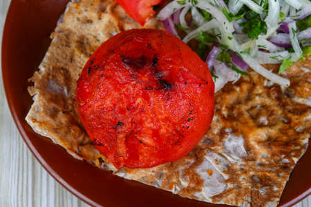 Grilled tomato seved bread, onion rings, herbs and salad leavesの写真素材