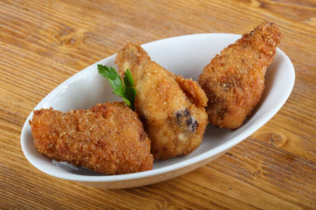 Fried chicken legs with parsley on the wood background
