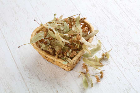 Dry linden flowers in the basket on wood backgroundの写真素材