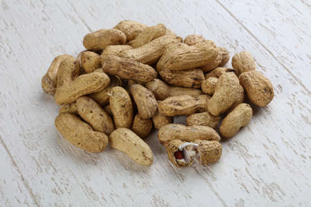 Peanuts in the bowl on the wood background