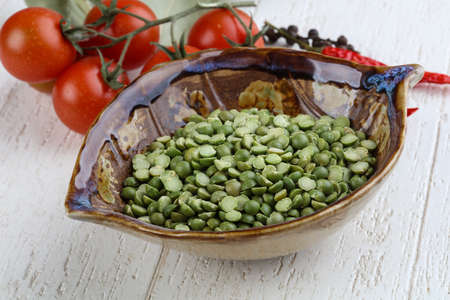 Dry green peas in the bowl on wood background