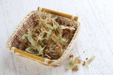Dry linden flowers in the basket on wood backgroundの写真素材