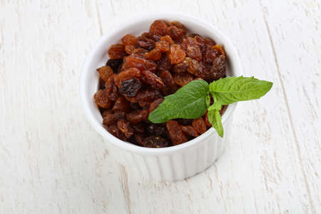 Raisin in the bowl on the wood backgroundの写真素材