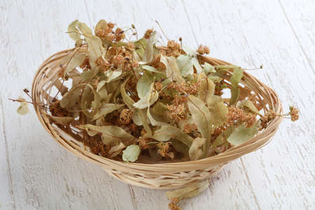 Dry linden flowers in the basket on wood backgroundの写真素材