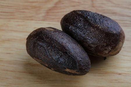 Nutmeg on the wood background - ready for cooking