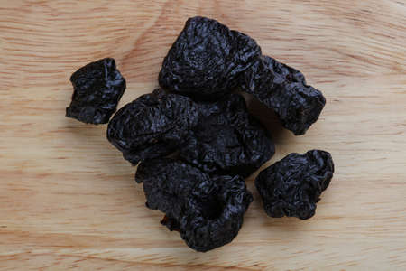 Dried plums heap on the wood backgroundの写真素材