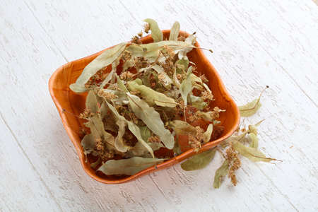 Dry linden flowers in the basket on wood backgroundの写真素材