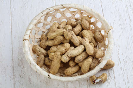 Peanuts in the bowl on the wood background