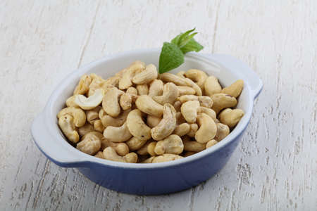 Cashew nuts in the bowl on wood backgroundの写真素材