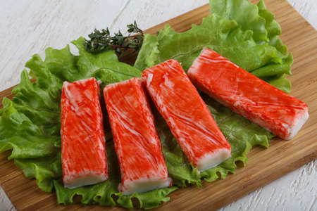 Crab sticks with salad leaves on wood backgroundの写真素材