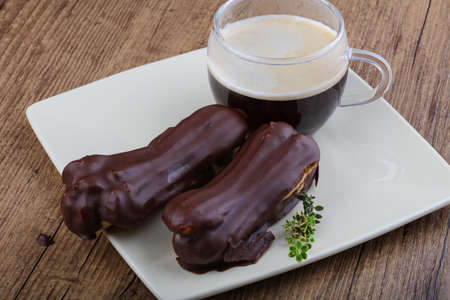 Eclairs with chocolate with coffee on wood bacground