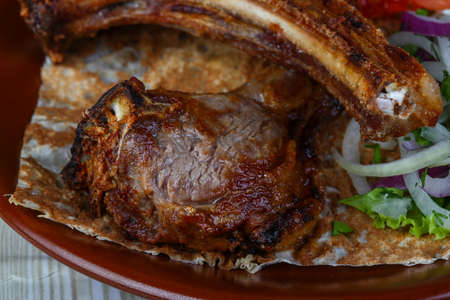 Grilled lamb ribs with onion, salad and sliced tomatoの写真素材