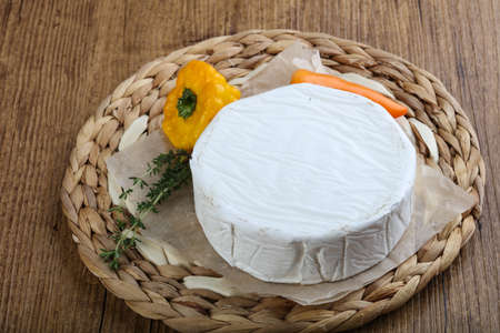 Camembert cheese with thyme on wood background
