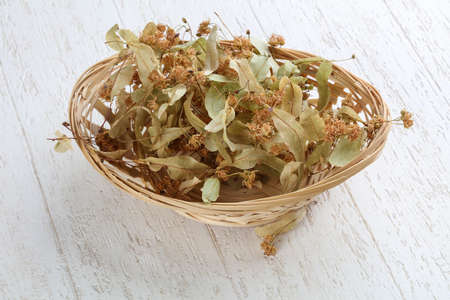 Dry linden flowers in the basket on wood backgroundの写真素材