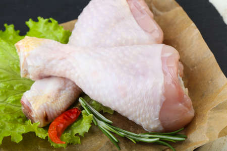 Raw chicken leg with herbs and spices ready for cookingの写真素材