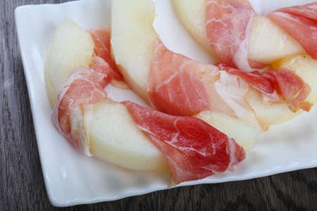 Melon with prosciutto on the wood backgroundの写真素材