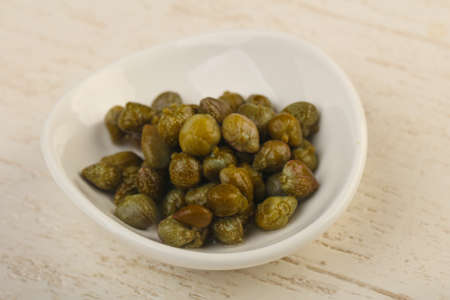Marinated capers in the bowl over wood backgroundの写真素材