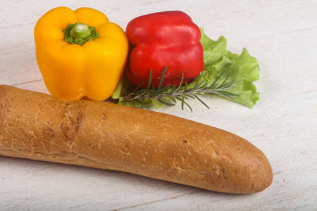 Crust baguette with vegetables over wooden backgroindの写真素材