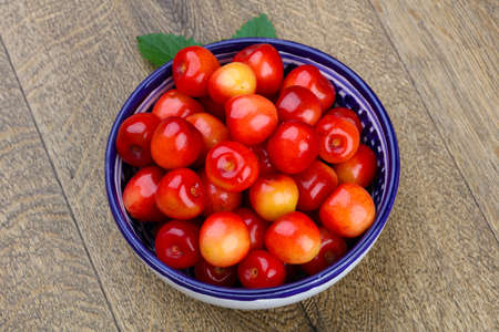 Sweet cherry in the bowl on wood backgroundの写真素材