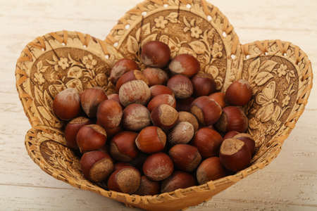 Hazelnut heap in the basket over wooden background