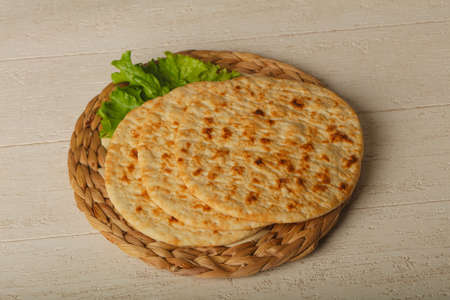 Pita bread with salad over wood background