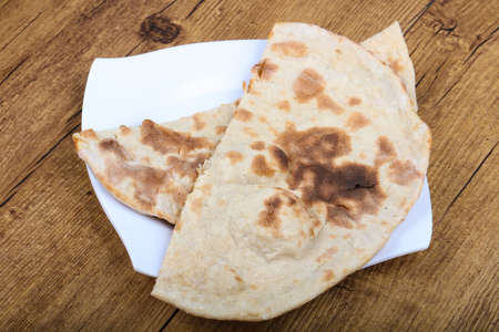 Indian bread naan in the plate on wood background