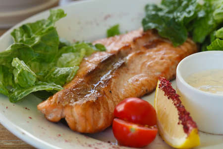 Grilled salmon steak with sauce and salad leaves