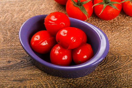 Pickled cherry tomatoes heap on the wooden backgroundの写真素材