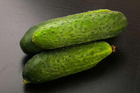 Cucumbers over the black wooden backgroundの写真素材