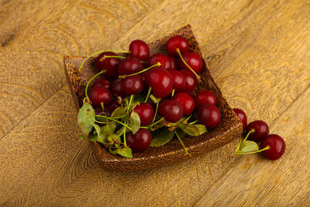 Cherry berries in the bowl on wood background