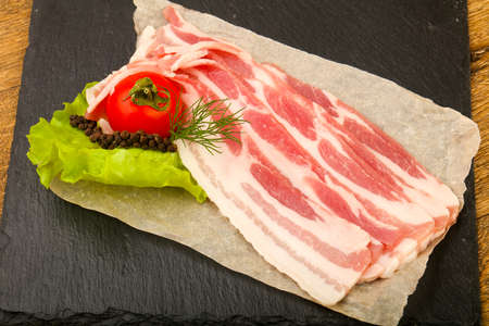 Raw bacon served dill over the wooden backgroundの写真素材