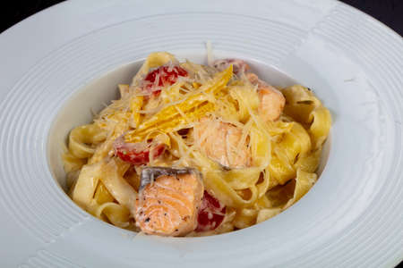 Delicious cheese pasta with salmon and cherry tomatoesの写真素材