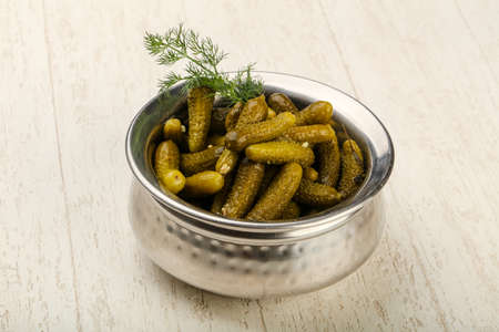 Picled cucumbers in the bowl over wooden backgroundの写真素材