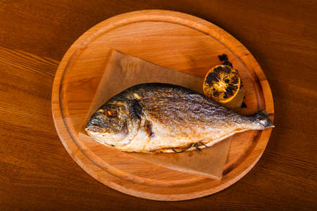 Grilled dorada with lemon over wooden backgroundの写真素材