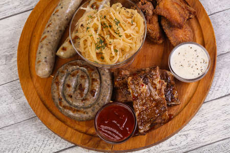 Meat plate with grilled sausages, ribs and chicken wings served cabbageの写真素材