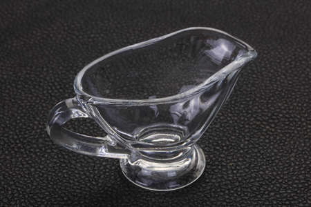Empty glass gravy boat over black backgroundの写真素材