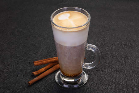Capuccino in the glass served cinnamon sticks