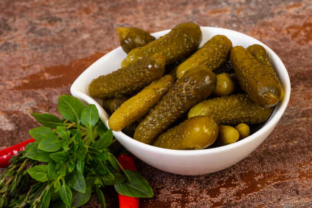 Pickled small cucumbers in the bowl served herbsの写真素材
