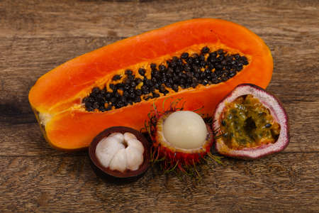 Tropical fruit mix - Papaya, passionfruit, mangosteen, rambutan over woodenの写真素材