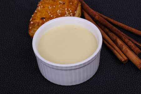 Condenced milk in the bowl with sinnamon sticks and pastryの写真素材