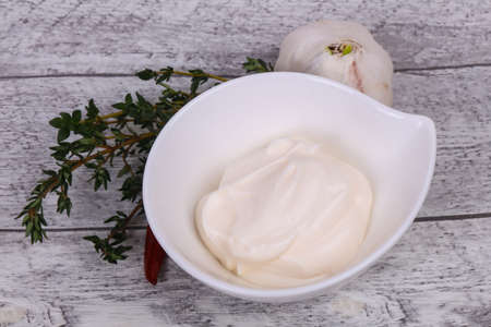 Mayonnaise sauce in the white bowl served thyme, red pepper and garlicの写真素材