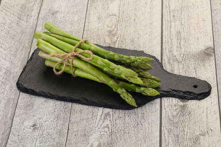 Raw asparagus heap over the wooden boardの写真素材