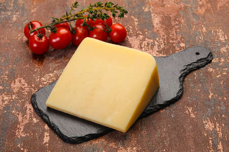 Hard parmesan cheese piece over wooden backgroundの写真素材