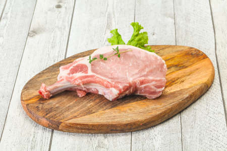 Raw pork bone steak over wooden backgroundの写真素材