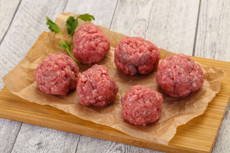 Raw meatball over wooden background ready for cookingの写真素材