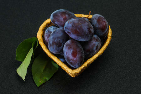 Ripe plum heap in the basket with leavesの写真素材