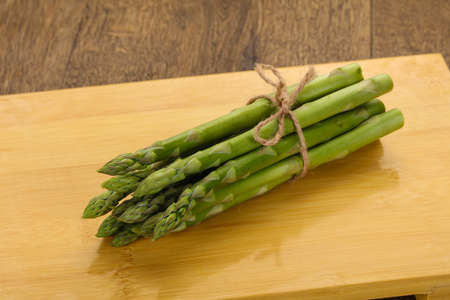 Raw asparagus heap over the wooden boardの写真素材