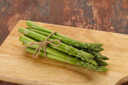 Raw asparagus heap over the wooden boardの写真素材